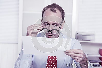 Short sighted at work - balding businessman looking through glasses at document Stock Photo