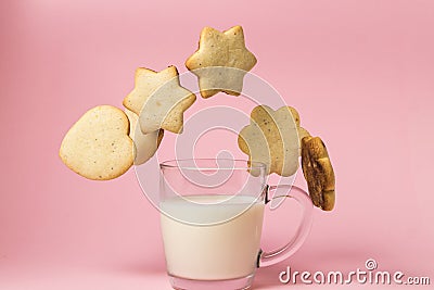 Shortbread cookies and a glass of milk on a pink background. The cookie falls into a glass of milk. Stock Photo