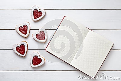 Shortbred heart shaped cookies with empty notebook frame, composition on white wooden background for Valentines day. Stock Photo