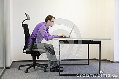 Shortsighted businessman bad sitting posture at laptop Stock Photo