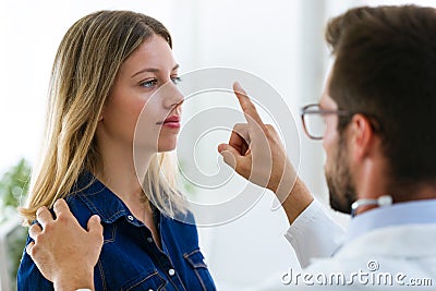 Attractive male doctor ophtalmologist checking the eye vision of beautiful young woman in modern clinic. Stock Photo