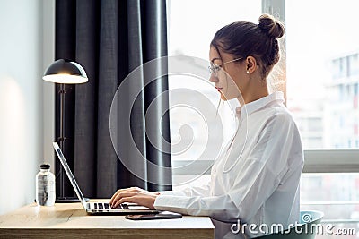 Concentrated beautiful businesswoman working with her laptop on the desk at the hotel room Stock Photo