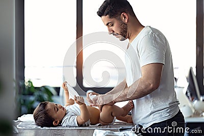 Concentrated young father changing the nappy to his little baby at home Stock Photo