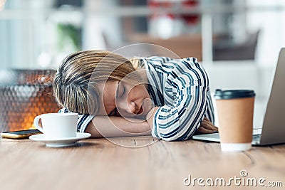 Exhausted young business woman who has fallen asleep while working wirh laptop in living room at home Stock Photo