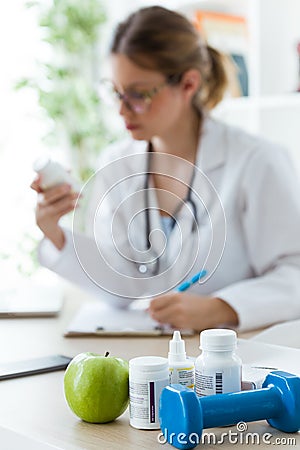 Female dietician holding a nutritional supplement while writing the properties in the consultation. Stock Photo