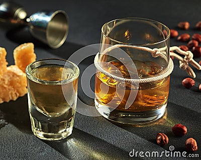 Shot of cold tequila and goblet of whiskey with ice Stock Photo