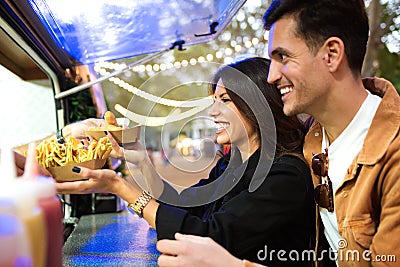 Group of attractive young friends choosing and buying different types of fast food in eat market in the street. Stock Photo