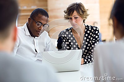 Group of intelligent young businesspeople working with laptop on coworking place Stock Photo