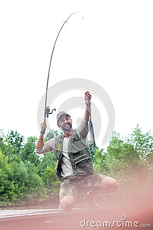 Shot of happy father catching fish at lakeshore Stock Photo