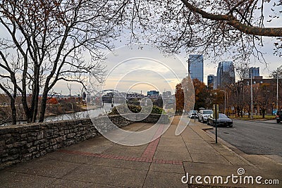 A shot of a long sidewalk with red brick with gorgeous autumn trees and parked cars along the street with powerful clouds Editorial Stock Photo
