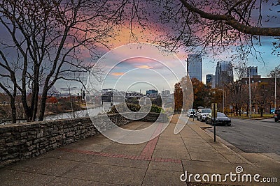 A shot of a long sidewalk with red brick with gorgeous autumn trees and parked cars along the street with powerful clouds Editorial Stock Photo