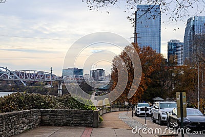 A shot of a long sidewalk with red brick with gorgeous autumn trees and parked cars along the street with powerful clouds Editorial Stock Photo