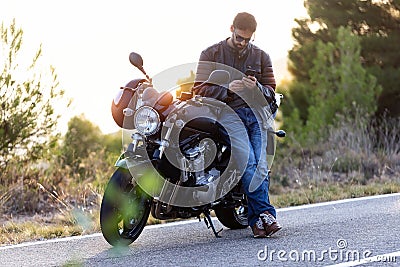 Man biker talking on the phone to the insurance of his motorcycle after having suffered a breakdown on the road Stock Photo