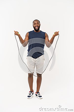 Shot of masculine man skipping rope. Muscular young man exercising with jumping rope against grey background Stock Photo