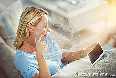 Timeout with her tablet. Shot of a mature woman relaxing on the sofa with a digital tablet. Stock Photo