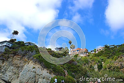 A shot of the mountain side at the beach with luxury homes on top of a lush green hillside at 1000 steps beach Editorial Stock Photo