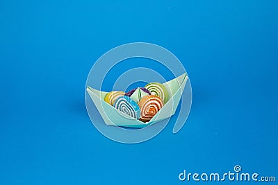 Shot of an origami paper ship full of tasty marmalade candies on a pastel blue background Stock Photo