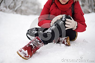 Shot of person during falling in snowy winter park. Woman slip on the icy path, fell, injury knee and sitting in the snow Stock Photo