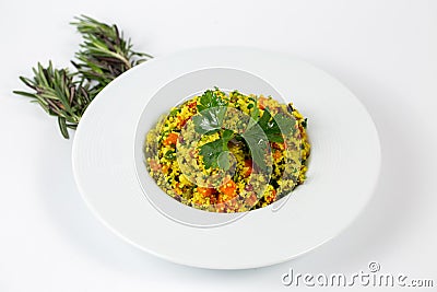 Shot of a a plate of Couscous with vegetables on a white table decorated with green plants Stock Photo