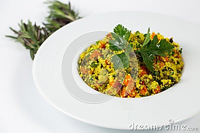 Shot of a a plate of Couscous with vegetables on a white table decorated with green plants Stock Photo