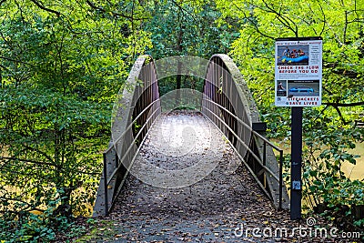 A shot of a rust colored iron bridge covered in fallen leaves over the brown waters of the Chattahoochee silky brown river Editorial Stock Photo