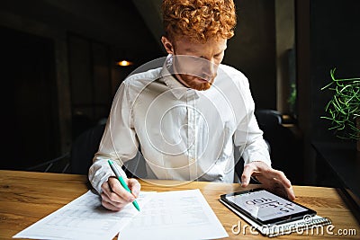 Shot of serious readhead young freelancer working at cafe Stock Photo