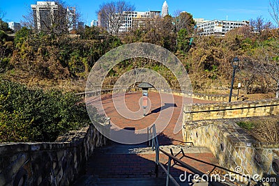 a shot of a staircase in the park with a view of the cityscape with skyscrapers and blue sky at Little Sugar Creek Greenway Editorial Stock Photo