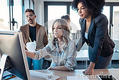 Successful business multiage team standing around computer for presentation of work in the coworking space Stock Photo