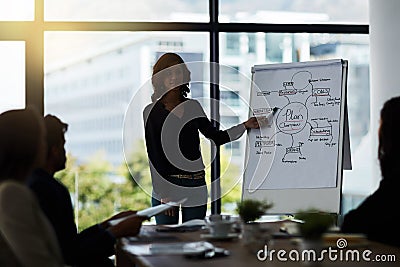 Sharing her thoughts with the team. Shot of a team of silhouetted businesspeople attending a meeting in the boardroom. Stock Photo