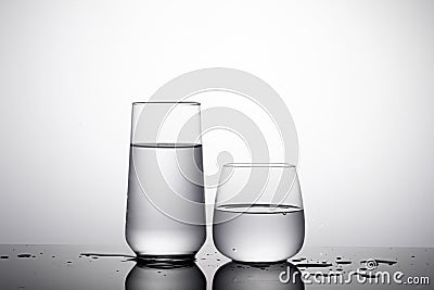 Shot of two glass of water - highball glass and whiskey glass on the white surface with shadows Stock Photo