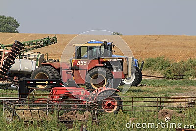 A shot of a Versatile farm tractor and Kubota tractor in a farm field with a fence and blue sky. Editorial Stock Photo