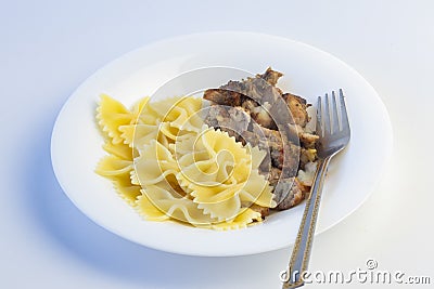 Shot on a white background. No isolation. White plate in it pasta and a piece of meat and a fork Stock Photo