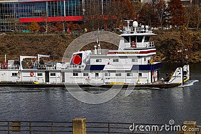 A shot of a white tug boat sailing in the Cumberland River with autumn colored trees on the banks of the river and bridges Editorial Stock Photo