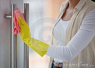 Everything your hands touch should be clean. Shot of a woman cleaning the handles of her door. Stock Photo