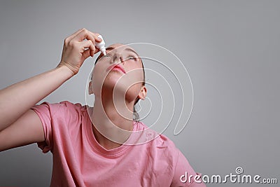 Shot of woman with injured eye inserting eye-drop. Health care and eyesight concept. Conjuctivitis. Space for space. Stock Photo