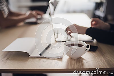 Shot of a woman`s hands typing on a laptop keyboard, with a cup of hot coffee near. Stock Photo