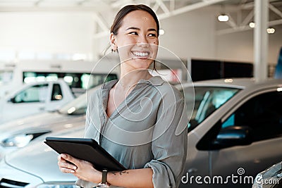 Get ready for the smoothest ride of your life. Shot of a woman using her digital tablet in a car dealership. Stock Photo
