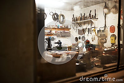 This is my workshop. Shot of a workshop filled with different types of tools inside someones home at night. Stock Photo