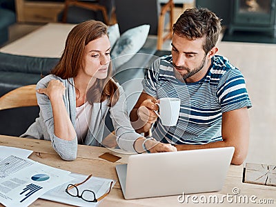 We always try to spend wisely online. Shot of a young couple working on their household budget and paying bills online. Stock Photo