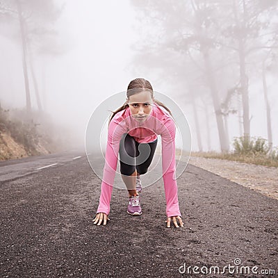 Psyched to run. Shot of a young female runner about to start a training session on a misty morning. Stock Photo