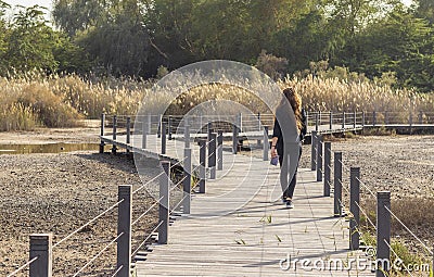 Shot of a young woman crossing wooden bridge. Outdoors Editorial Stock Photo