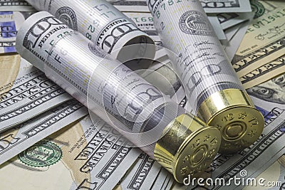 Shotgun shells loaded with hundred us dollar banknotes on different usa dollar bills background. Stock Photo