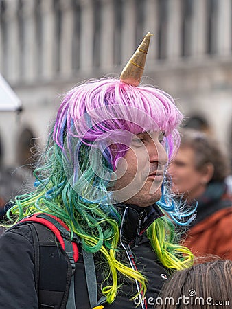 Shoulder street portrait of a middle-aged man in a unicorn costume - a bright multi-colored wig resembling the mane of a unicorn Editorial Stock Photo