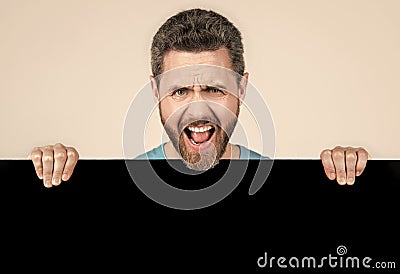 shouting bearded man behind blank black paper banner with copy space for advert, promotion Stock Photo