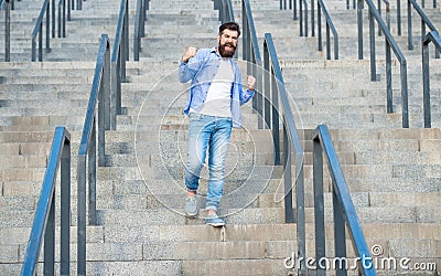 shouting hipster walk downstairs. full length of hipster with beard. hipster man outdoor at stairs Stock Photo