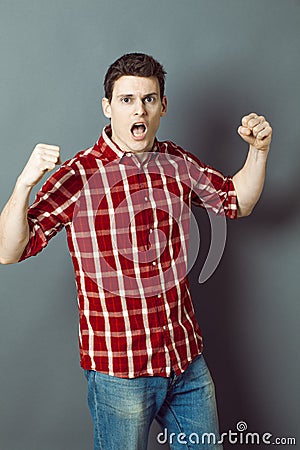 Shouting young man with arms raised expressing his exasperation Stock Photo