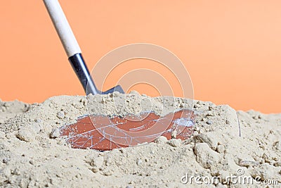 A shovel stuck in the sand there is a broken smartphone Stock Photo
