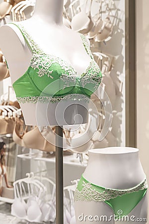 Showcase of lingerie shop. Mannequins in a beautiful lacy green bra and briefs. Close-up. Vertical Stock Photo