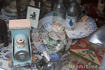 Showcase vintage store with a variety of junk and souvenir. Porcelain figurine frog, pharmacy bottles, boxes, paintings, sewing ma Editorial Stock Photo