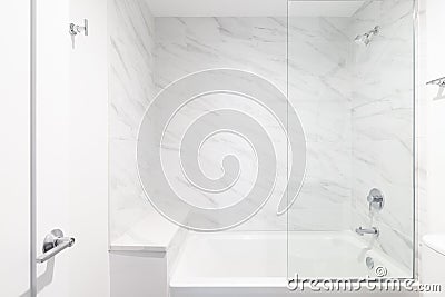 A shower with marble tiles, chrome faucet, and glass wall. Stock Photo